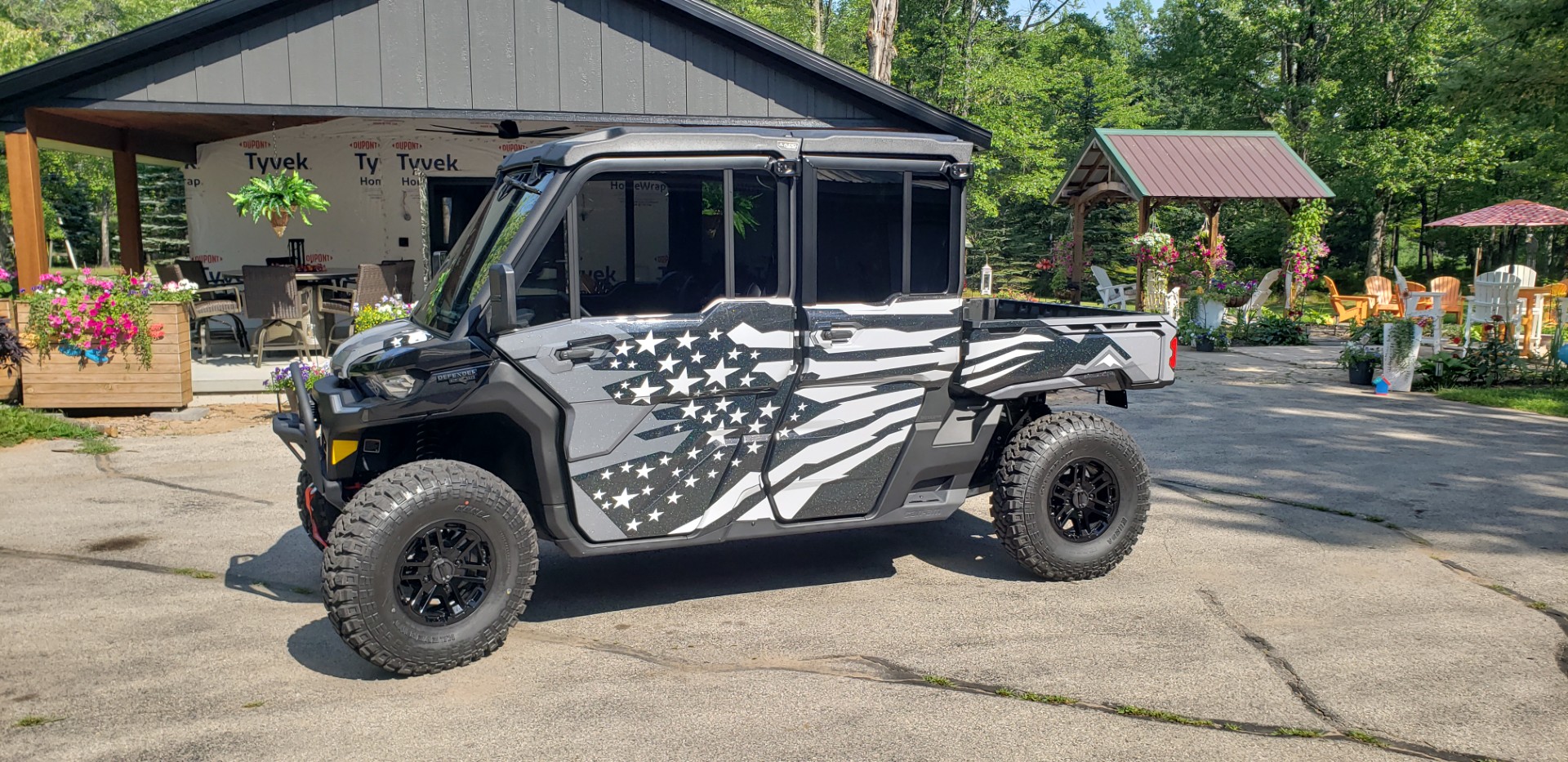 A Can-Am Defender Max with a black, charcoal gray, asphalt gray, and white Lef Alvarasson Merica custom wrap with halo flake laminate.